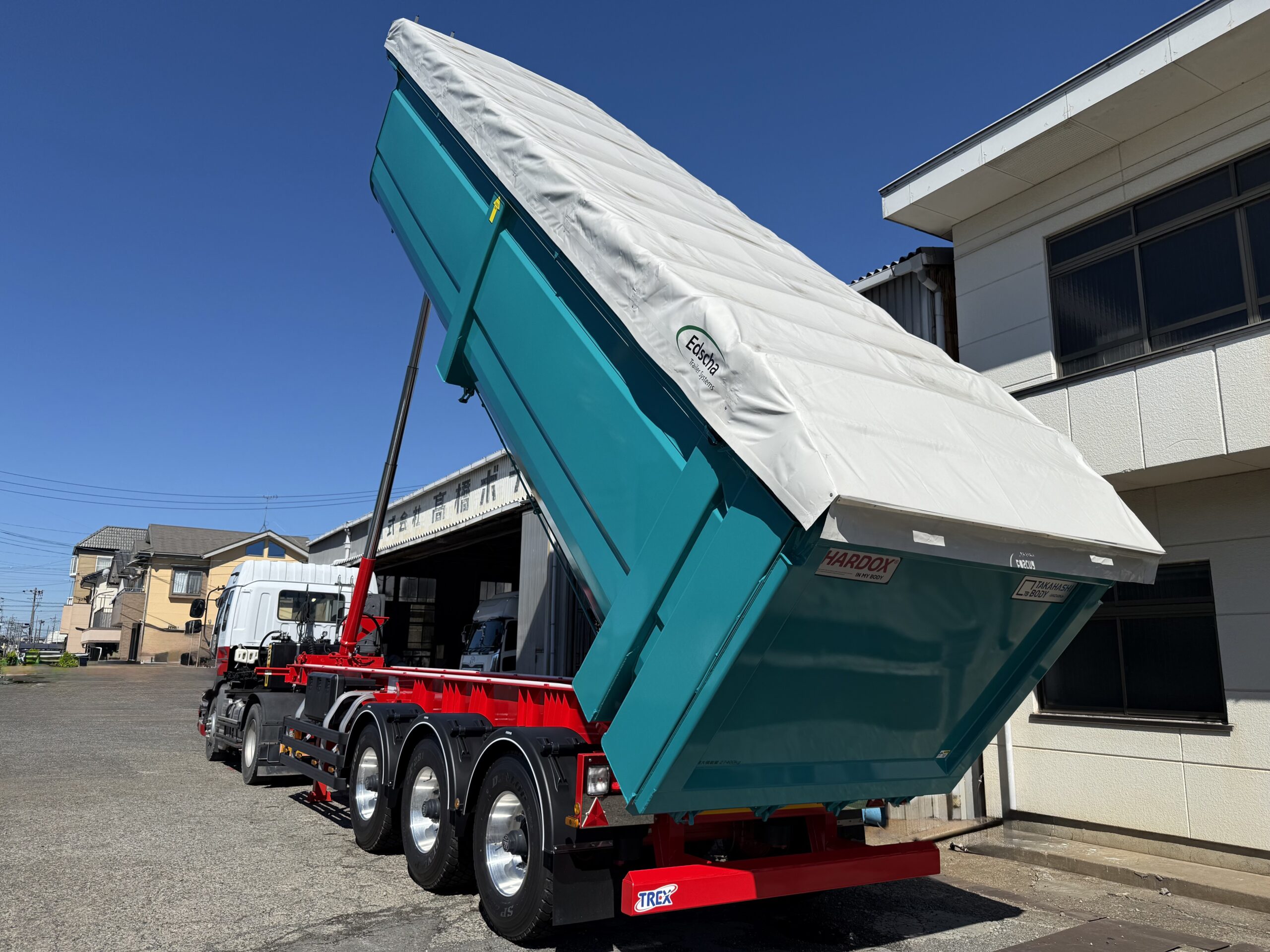 Edschaシートを閉じたままダンプアップするHARDOX®産業廃棄物収集運搬トレーラーダンプ36㎥を後方から見た様子